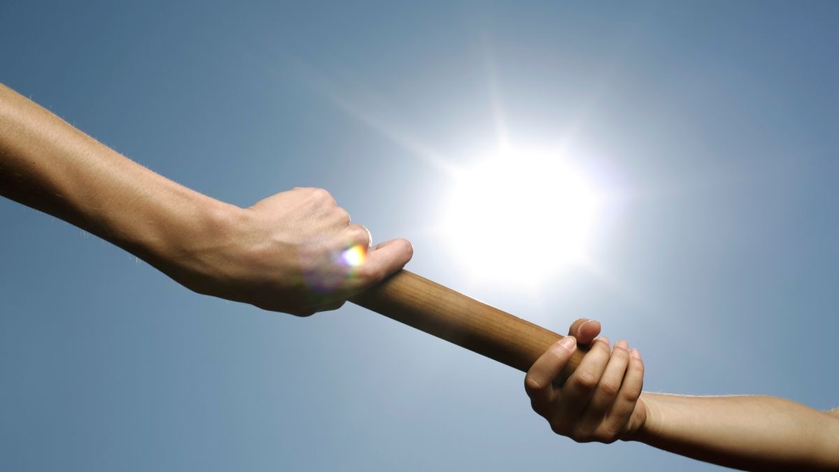 One hand passing a relay baton to another against a sunny sky, illustrating an agent handoff carrying context forward