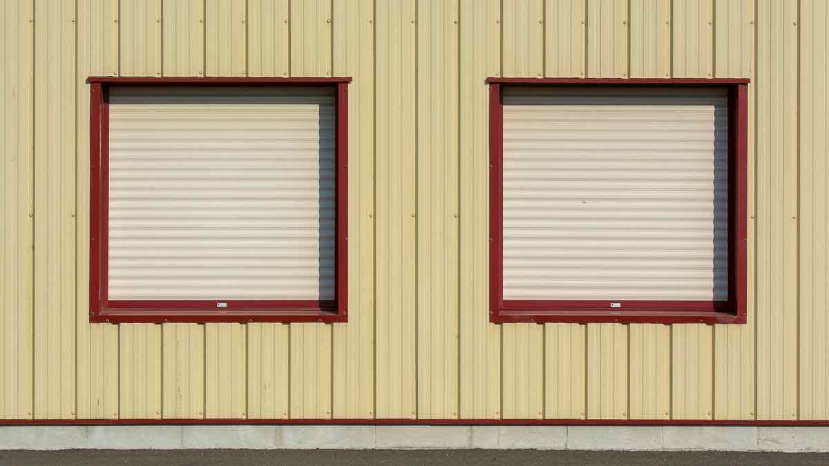 A row of closed metal roller shutters on a building facade