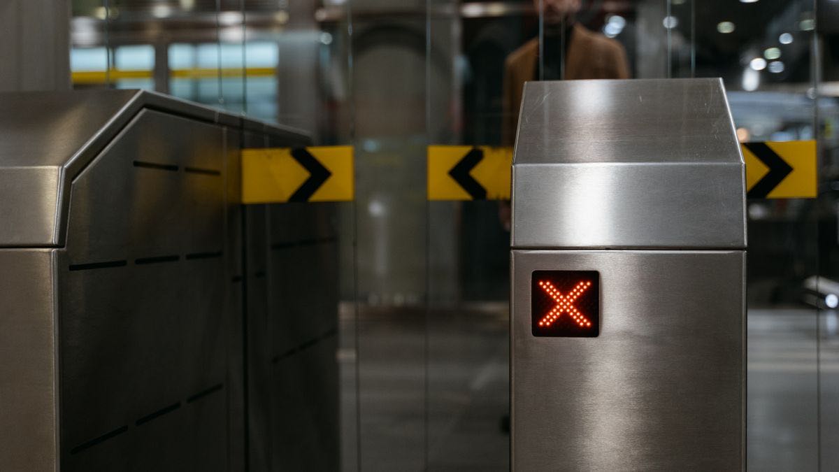 A turnstile gate at an entrance, illustrating approval-gated access to the official Reddit Data API