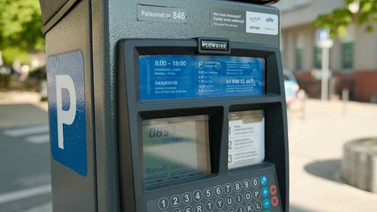 A modern blue-and-grey parking ticket machine with its tariff card and keypad clearly readable