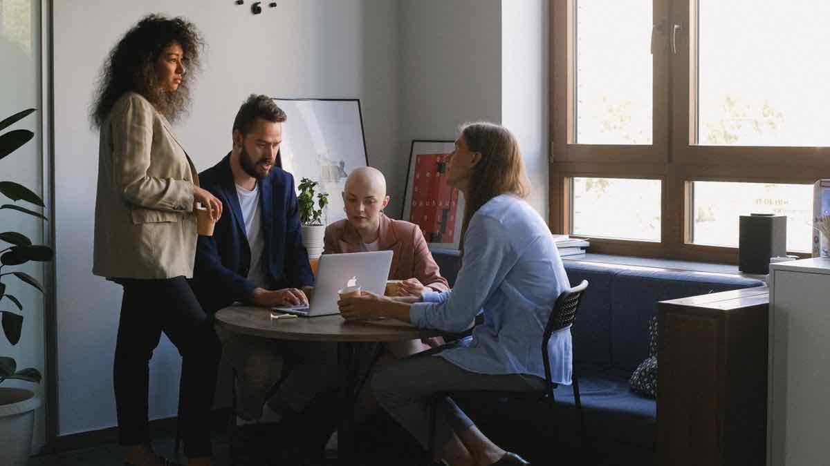 A team gathered around a laptop in an office, reviewing a data feed together