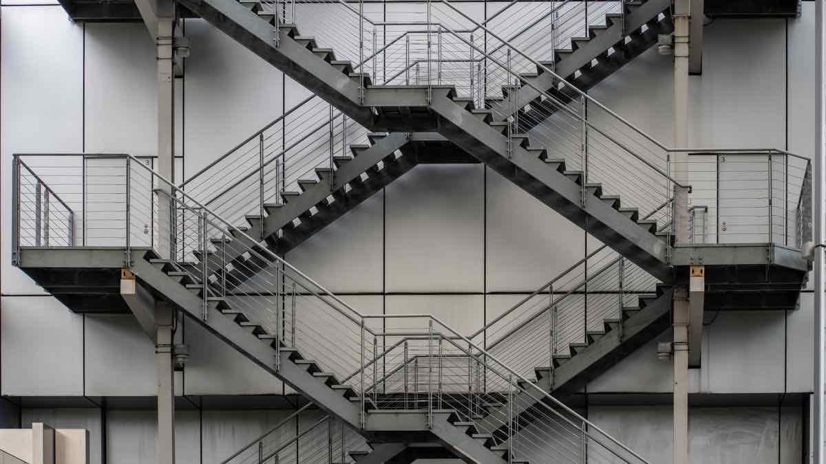 Interlocking steel staircases on a building facade, each flight a different length, illustrating Coresignal pricing tiers of uneven size