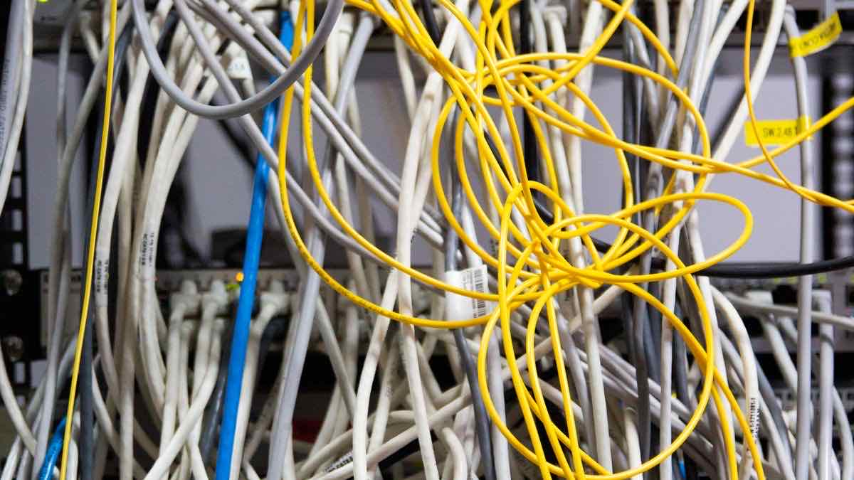 Tangled yellow and white network cables in a server rack, illustrating a task-queue integration with many moving parts
