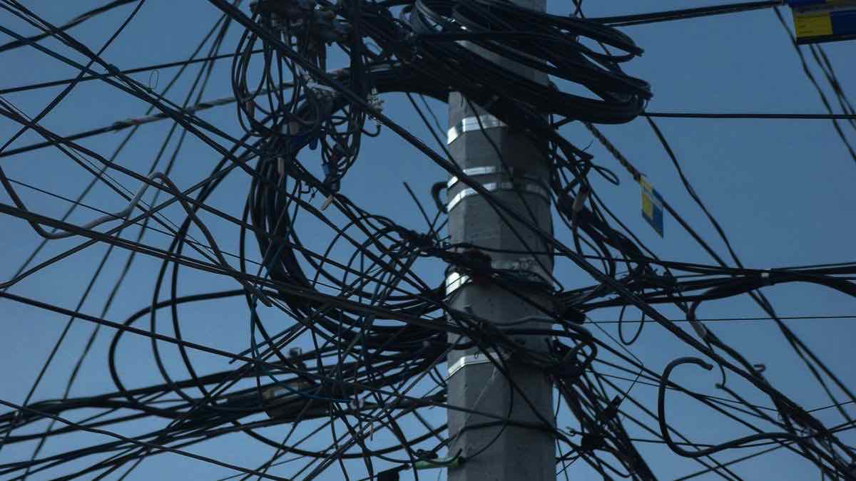 A tangle of black wires on a pole against blue sky, representing DataForSEO's complexity