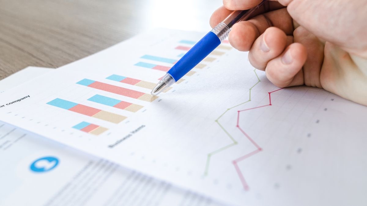 A hand with a pen reviewing printed charts and figures — the manual review step for flagged enrichment rows