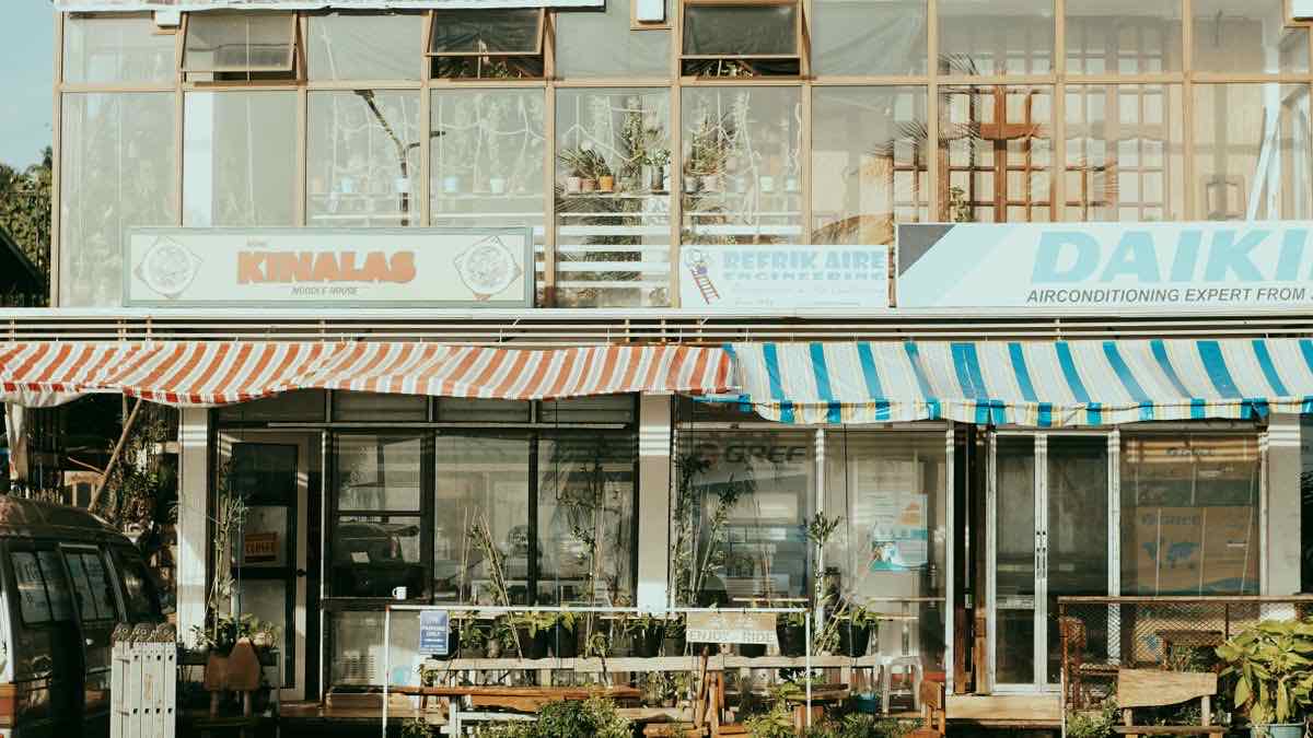 A row of local main-street storefronts at dusk, the kind of businesses a Maps-to-email lead pipeline targets