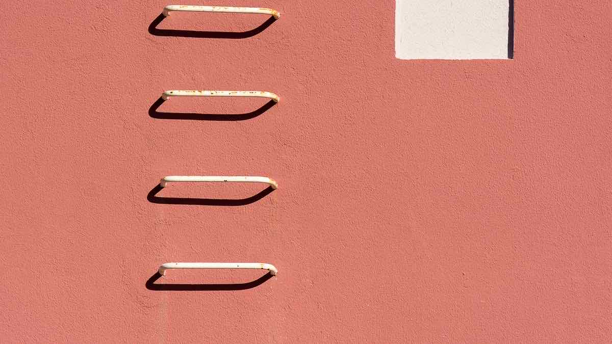 White metal rungs ascending a sunlit terracotta wall, representing the ladder of options after Google's JavaScript requirement