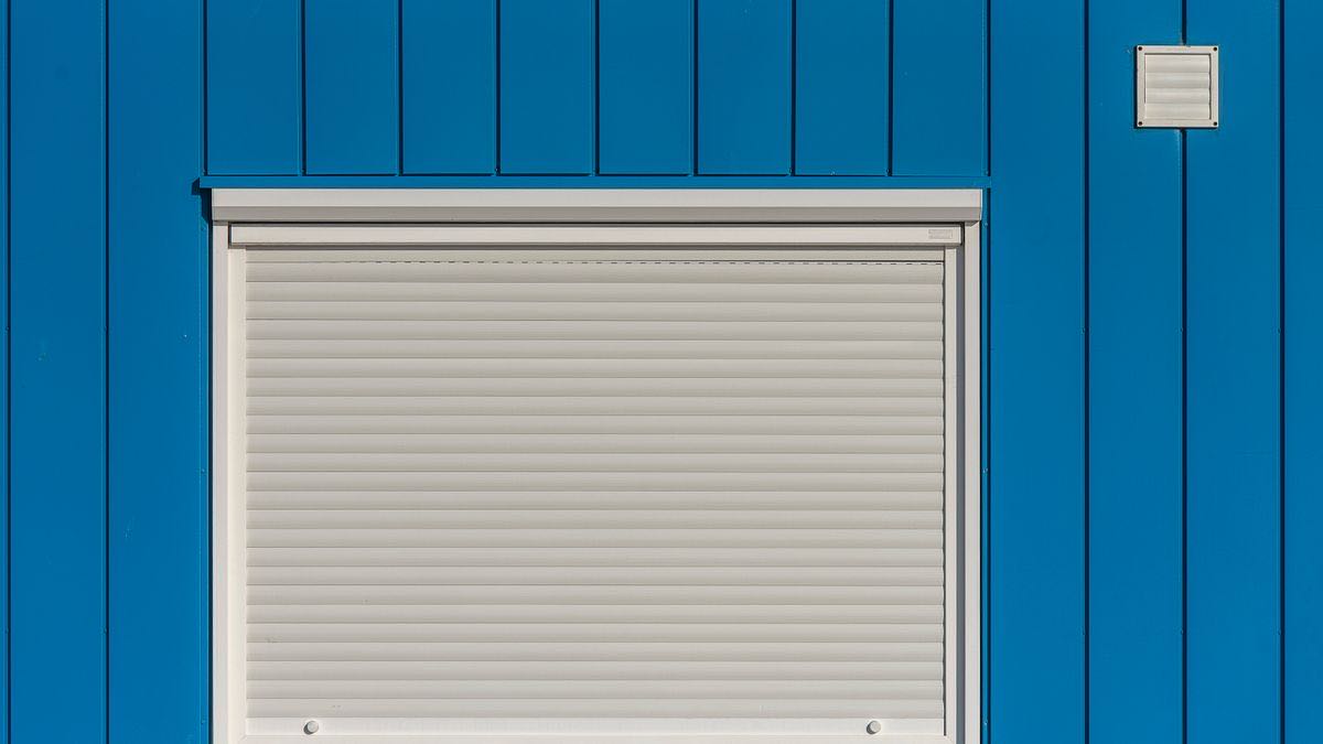 A white roller shutter pulled down on a blue wall, representing Google closing plain HTTP access