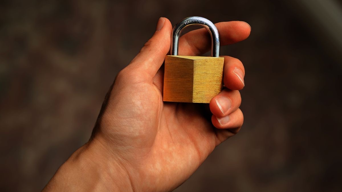A metal padlock held in a hand, a metaphor for the secure TLS handshake where a client's fingerprint is exposed