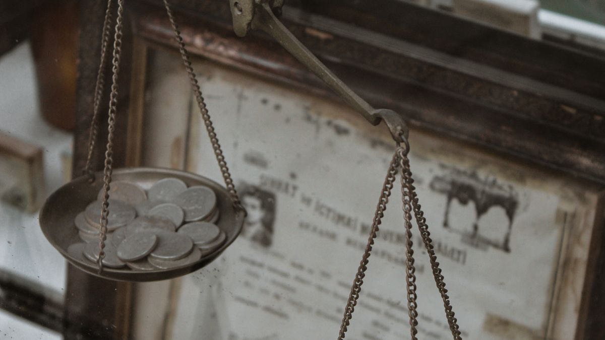 An antique weighing scale holding coins, photographed in a vintage collection room