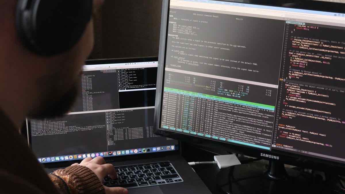 A developer at a dual-monitor setup running a Python script in a terminal alongside source code