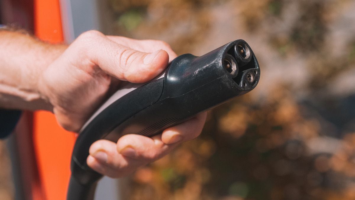 A hand holding a charging plug ready to connect — plugging live search into an AI app