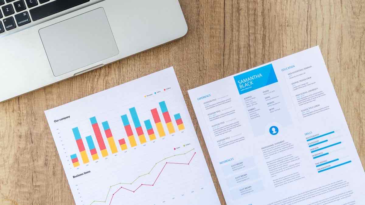 Printed bar and line charts next to a laptop, representing a competitor tracking report