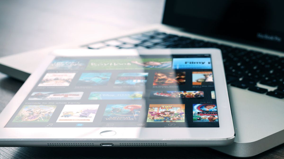 A tablet showing a grid of video thumbnails resting on a laptop keyboard, representing monitoring competitor video channels